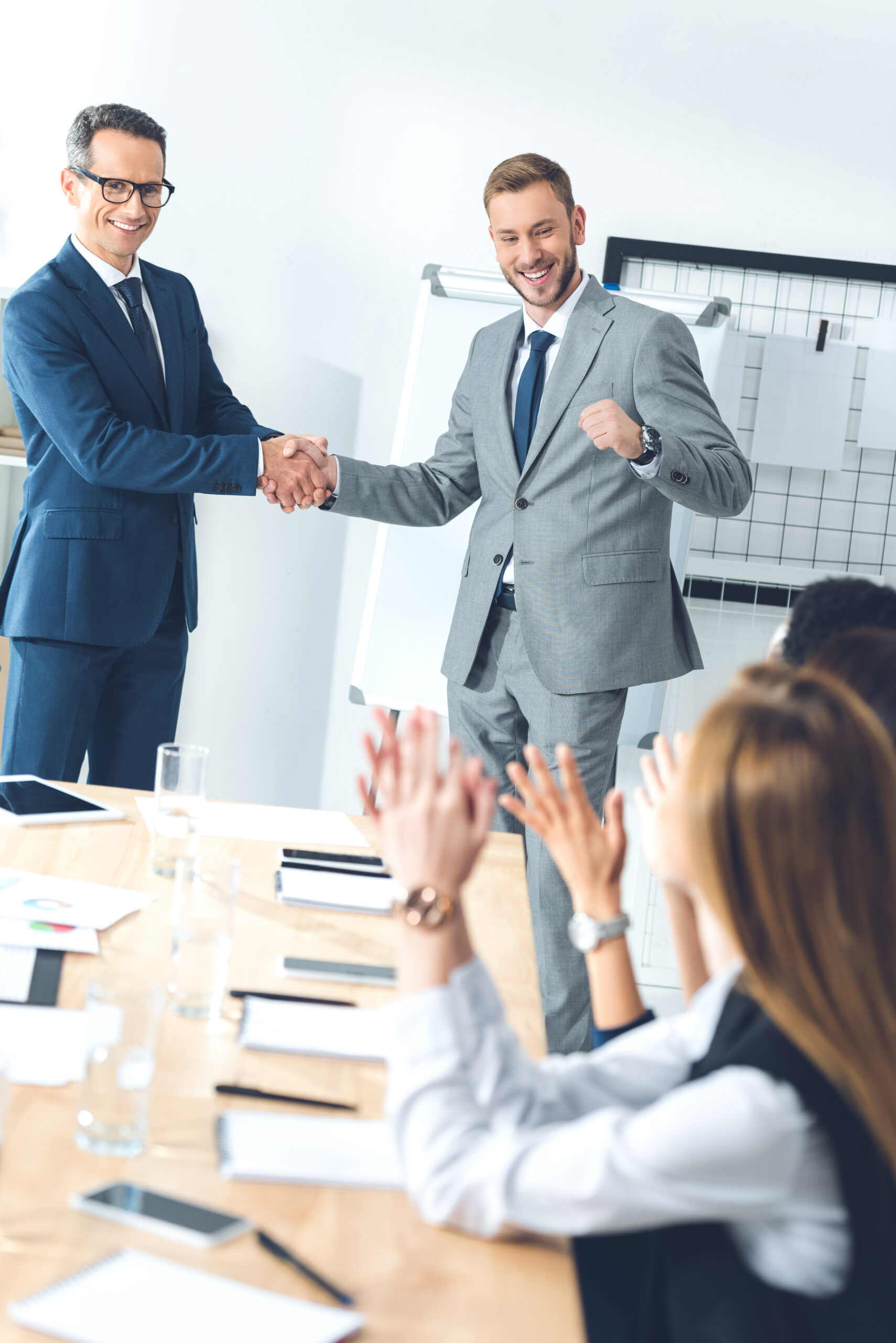 boss shaking hand of manager while colleagues clapping