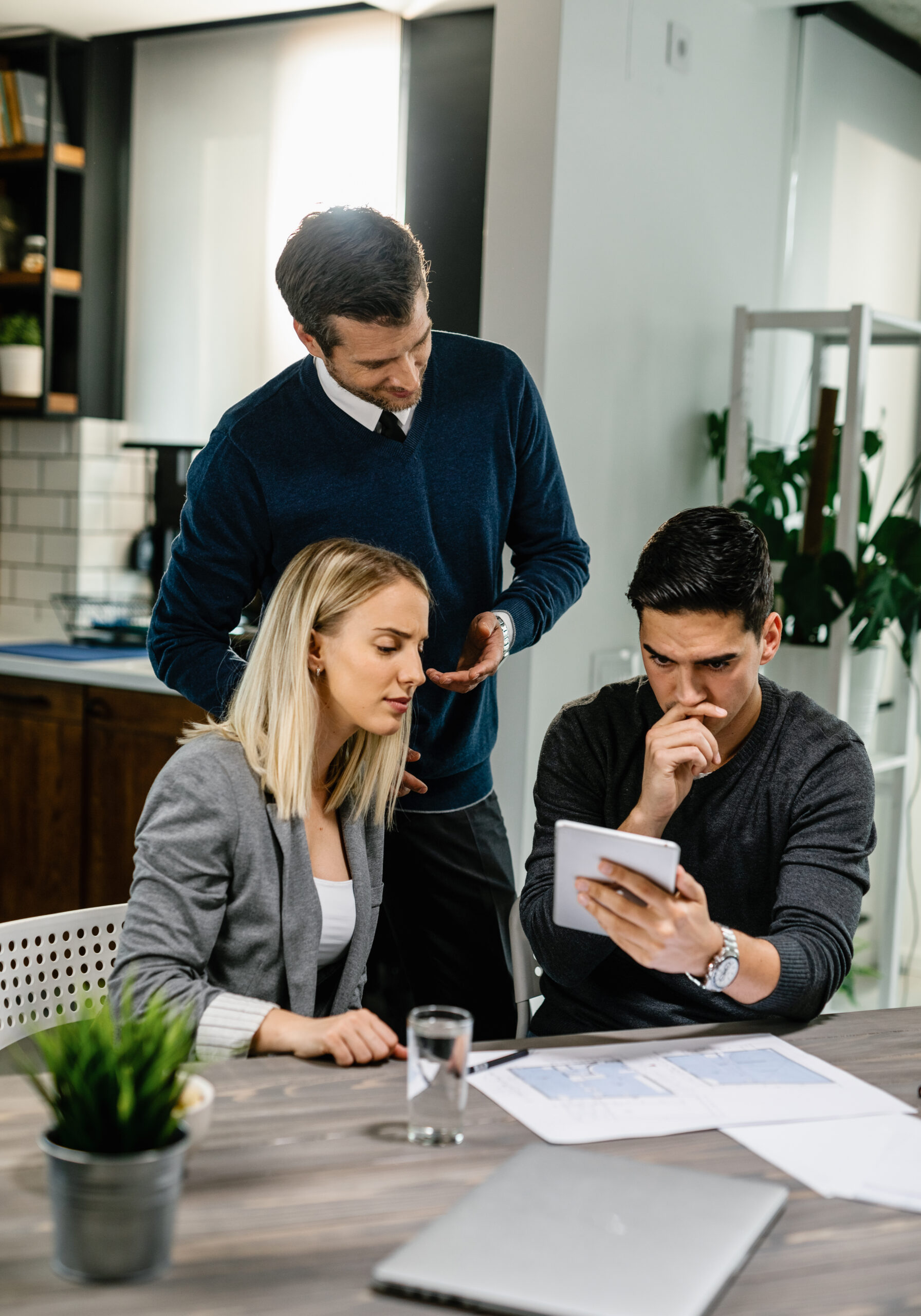 Young couple using touchpad while having a meeting with real estate agent at home. Young couple feeling uncertain while using digital tablet on a meeting with their insurance agent at home.